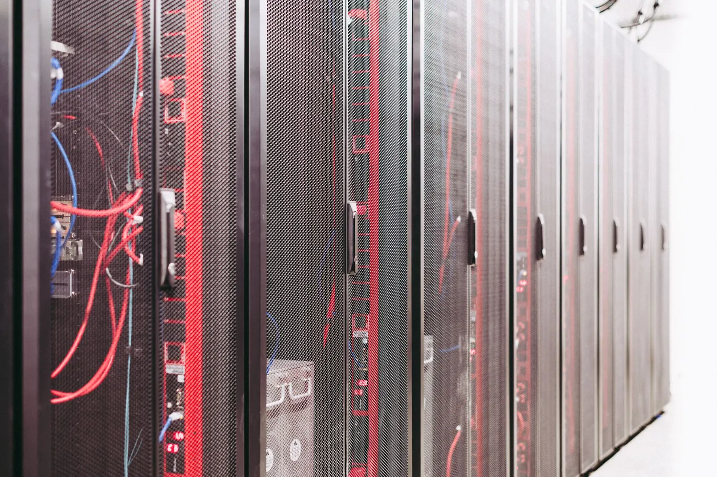 Open server rack with cabling beside closed rack cabinets